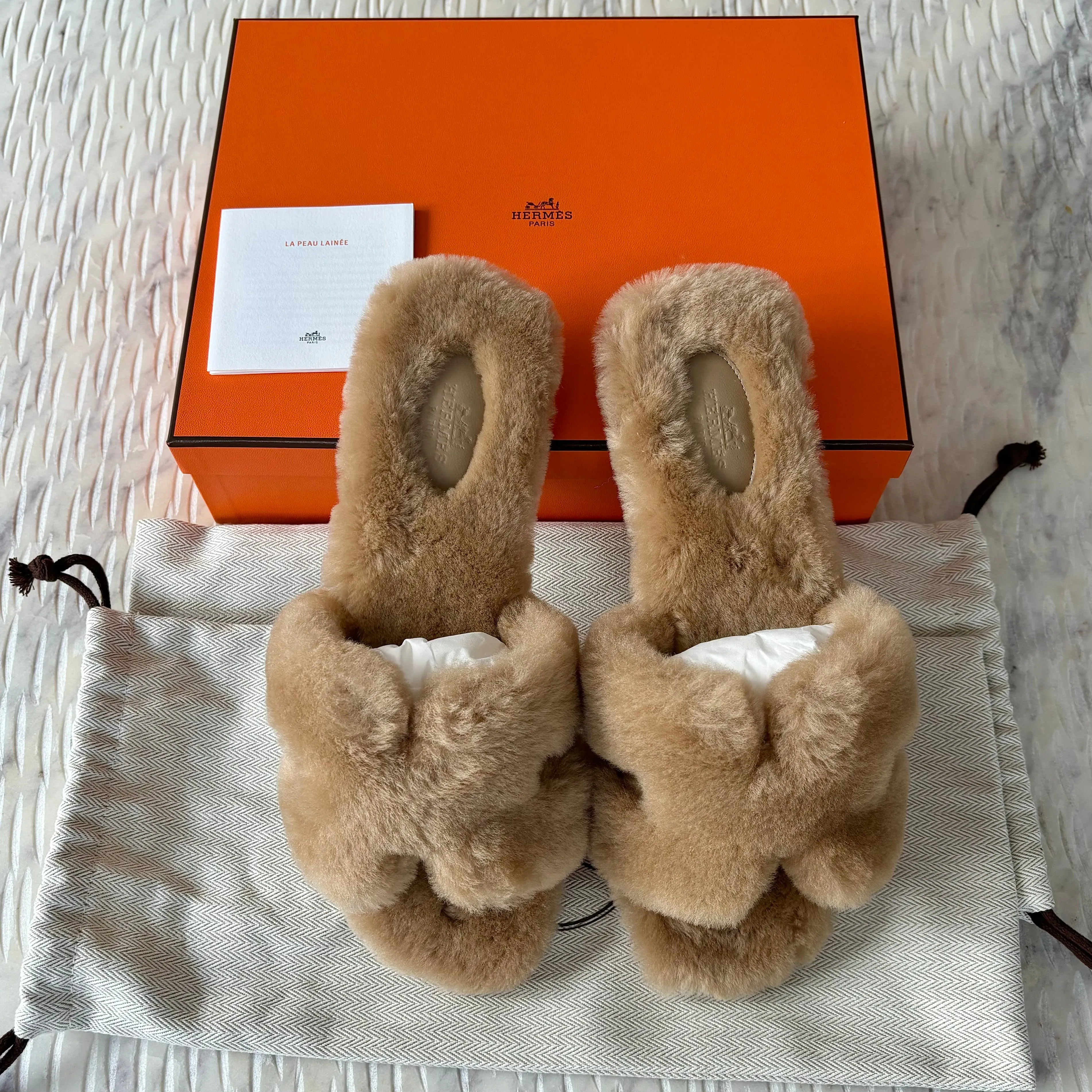 Sure! Here is the optimized title for the product you mentioned: Luxurious Hermes Shearling Oran Sandals in Elegant Beige